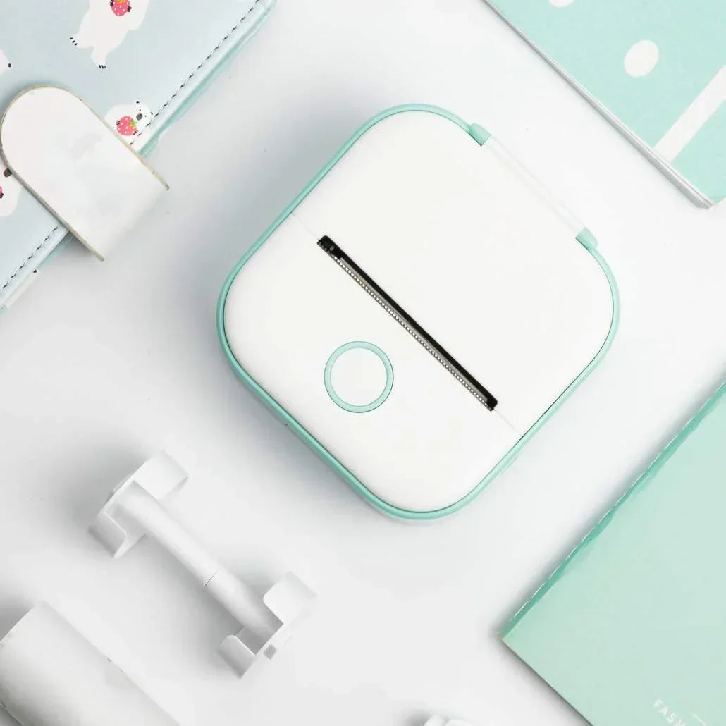 Compact white and teal portable printer on a white desk with stationery, ideal for on-the-go printing
