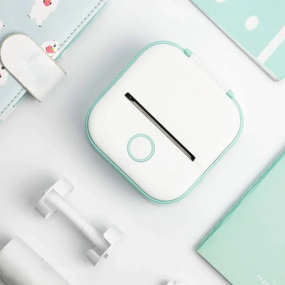 Compact white and teal portable printer on a white desk with stationery, ideal for on-the-go printing